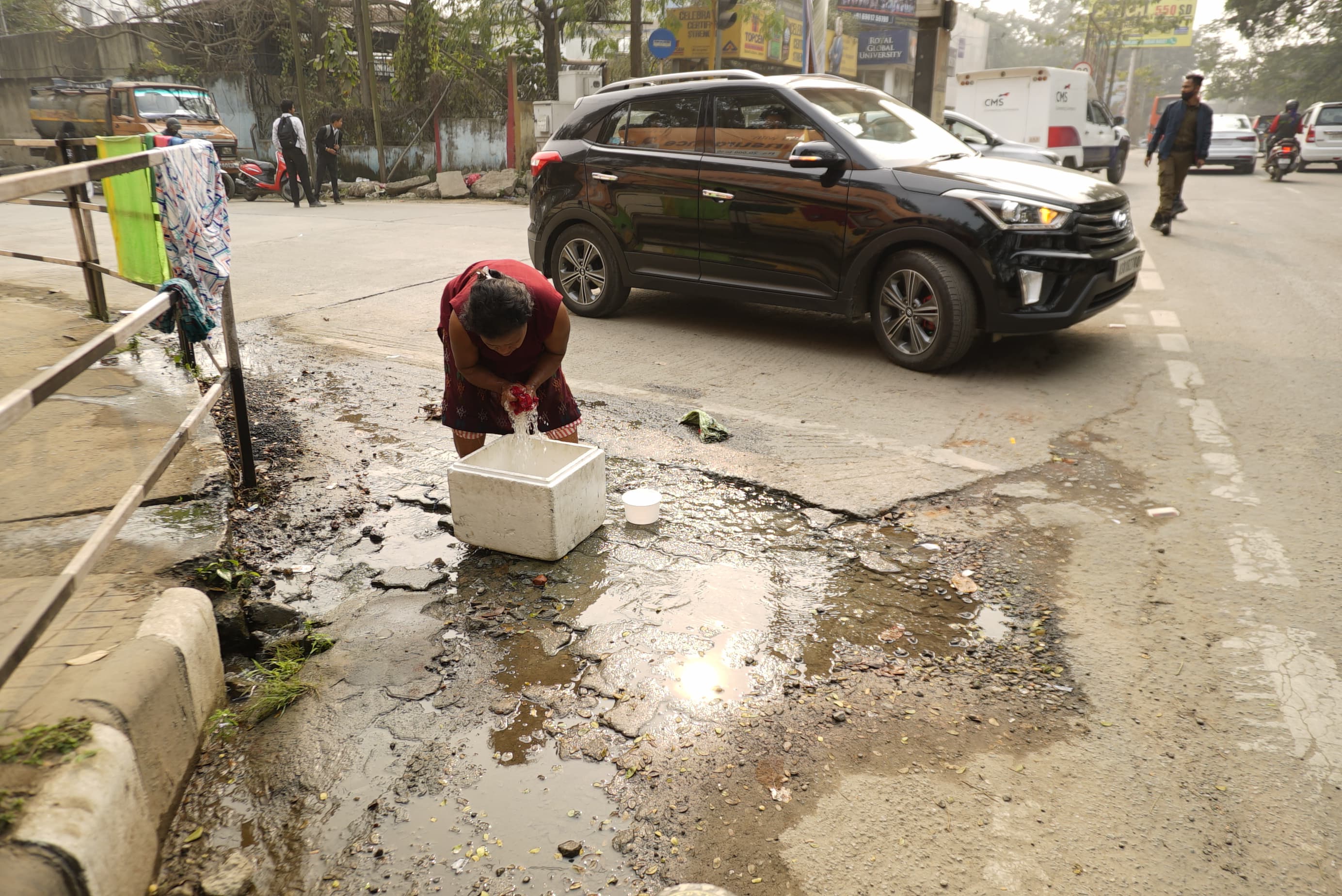 A woman washing a carton from the leaked water of a pipeline in Guwahati.